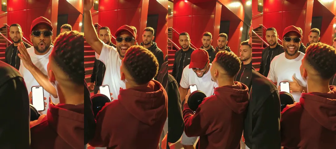 Four frames from one vertical Bulin 47 AI video outside a red-lit restaurant: a man in a red cap and black wraparound sunglasses rapping at a phone, raising an arm high, grinning with his head down, and talking to a friend seen from behind
