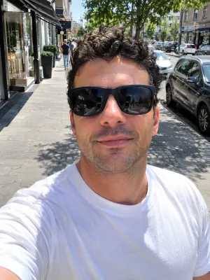 A man in dark sunglasses on a sunny street